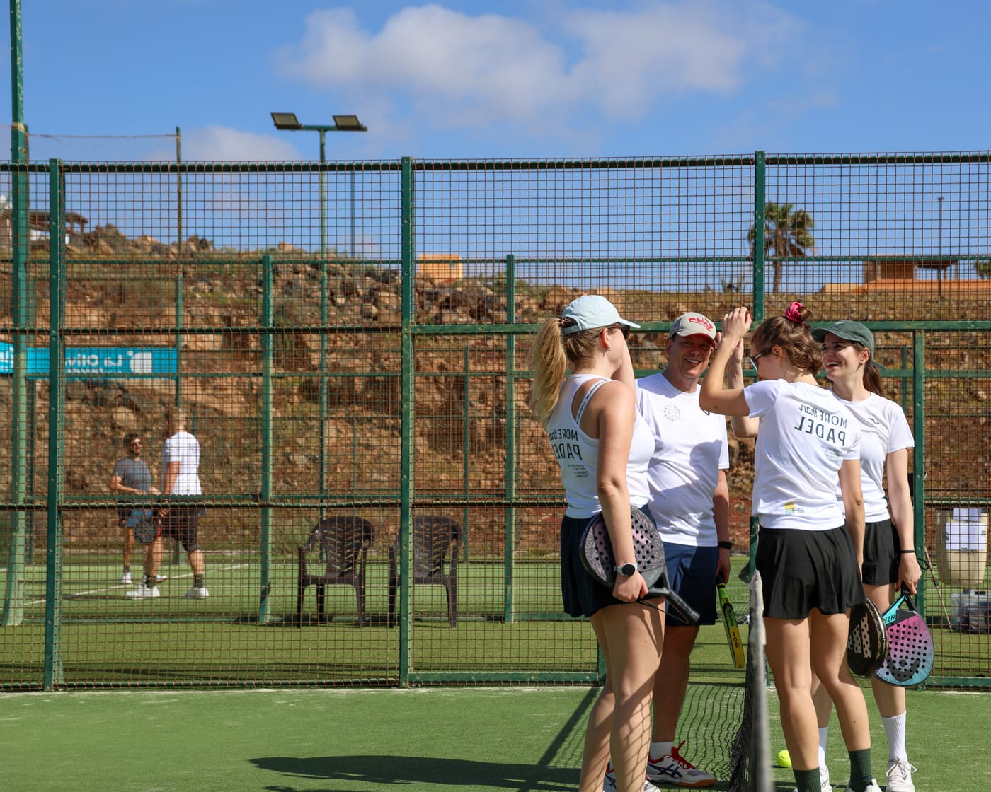 Teilnehmer klatschen sich nach dem Training auf dem Padelplatz ab